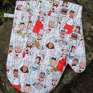 Puede incluir: Un guante de horno blanco con un patrón colorido de chefs que llevan sombreros blancos y sostienen varios utensilios de cocina. Los chefs están representados en un estilo de dibujos animados y tienen diferentes expresiones faciales.