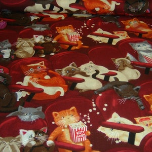 Könnte beinhalten: Ein roter Stoff mit einem sich wiederholenden Muster von Katzen, die in einem Kino sitzen. Die Katzen haben verschiedene Gesichtsausdrücke und halten Popcorn, Getränke und Handtaschen. Der Stoff hat einen Vintage-Look und -Feel.
