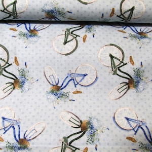 Op de afbeelding: Blauw en wit stof met een herhalend patroon van fietsen met bloemen in de manden. De achtergrond is lichtblauw met witte stippen.