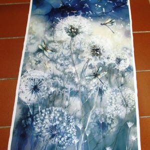 Op de afbeelding: Een stoffen paneel met een aquarelontwerp van paardenbloemen en libellen in blauw, wit en grijs. De paardenbloemen staan in verschillende bloeistadia, met zaden die in de lucht zweven. Libellen zijn verspreid.