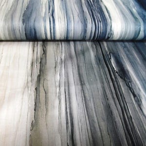 Pode incluir: Tecido abstrato com um padrão de listras verticais em tons de cinza, branco e azul. O tecido tem uma textura macia e fluida.