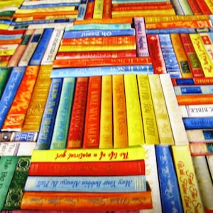 Könnte beinhalten: Stoff mit einem farbenfrohen Muster aus gestapelten Büchern. Die Bücher haben verschiedene Farben und Titel, darunter "The Life of a Material Girl" und "May Your Bobbin Always Be Full". Geeignet für Näh- und Bastelprojekte.