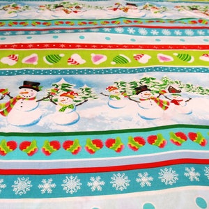 Könnte beinhalten: Ein blauer und grüner Stoff mit einem sich wiederholenden Muster aus Schneemännern, Schneeflocken und Weihnachtsmützen. Der Stoff hat einen weißen Hintergrund mit roten, grünen und blauen Streifen.