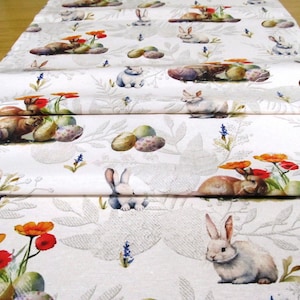 Può includere: Runner da tavola pasquale bianco con un motivo ripetuto di coniglietti, uova e fiori ad acquerello. Il design include fiori arancioni, rossi e blu, con uova verdi e marroni. Lo sfondo presenta un sottile motivo a foglie.