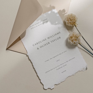 May include: A white wedding invitation with a torn edge, featuring the text "you are invited to celebrate with us as we become one Caroline Williams & Oliver Taylor Friday, the eighteenth day of June 2022 please join us at five thirty in the afternoon Cambium Farms ALTON"