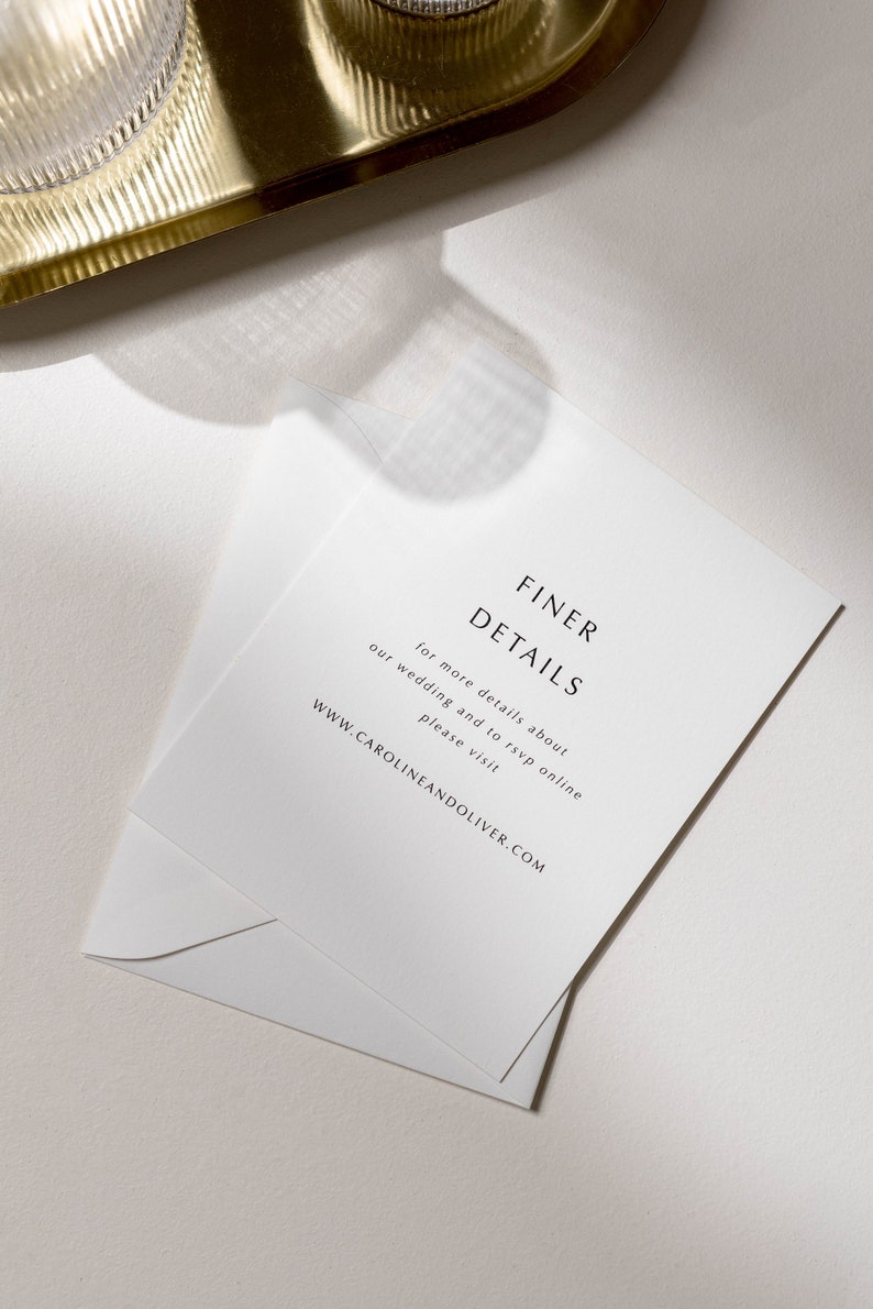 May include: White card with black text that reads "FINER DETAILS" and "for more details about our wedding and to rsvp online please visit WWW.CAROLINEANDOLIVER.COM".