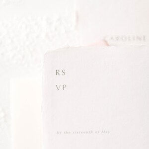 May include: A white RSVP card with the text "RS VP" and "by the sixteenth of May". The card also has lines for the number attending, joyfully accepts, and regretfully declines.
