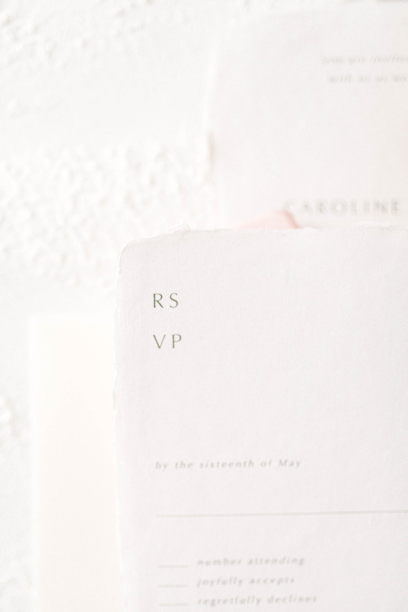 May include: A white RSVP card with the text "RS VP" and "by the sixteenth of May". The card also has lines for the number attending, joyfully accepts, and regretfully declines.