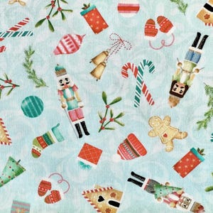 May include: A light blue fabric with a repeating pattern of Christmas-themed illustrations. The design includes candy canes, nutcrackers, gingerbread men, ornaments, gift boxes, and sprigs of mistletoe in red, green, and white.