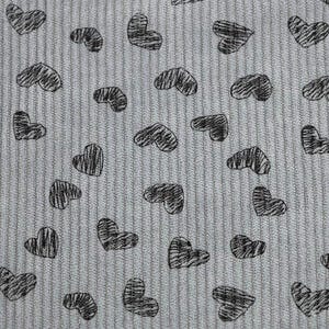 May include: Close-up of a light gray fabric with a ribbed texture. The fabric is patterned with numerous black, hand-drawn heart shapes. The hearts vary in size and are scattered across the surface, creating a playful design.