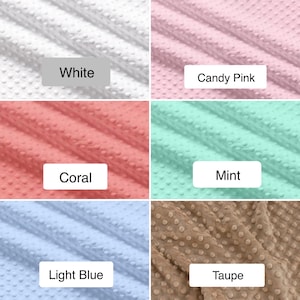 May include: A collection of six fabric swatches in various colors, including white, candy pink, coral, mint, light blue, and taupe. Each swatch has a textured, dotted pattern and a label indicating its color.