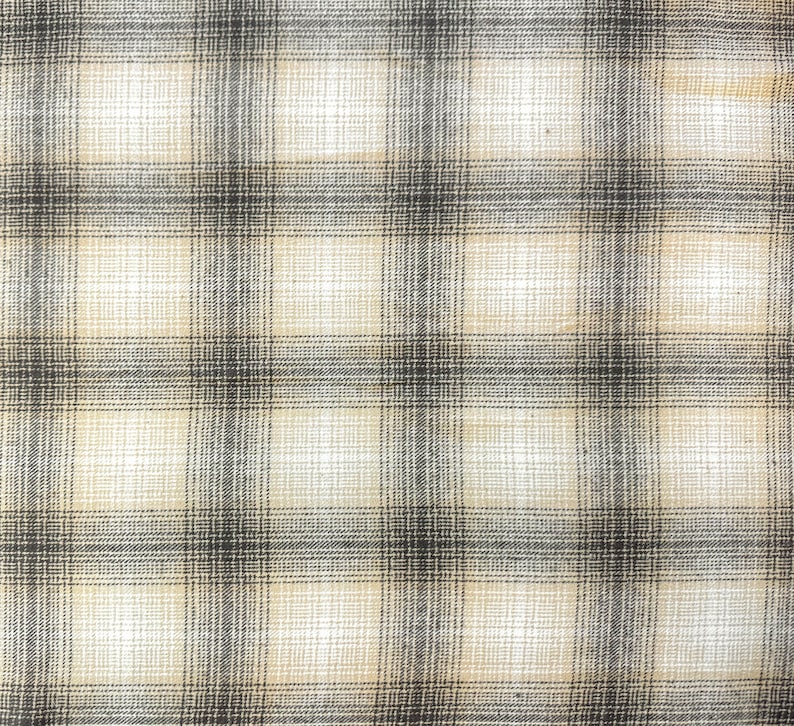 May include: A beige and black plaid fabric with a woven texture.