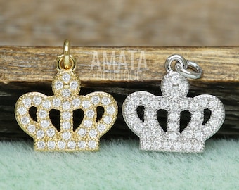 May include: Two silver and gold crown charms with clear cubic zirconia stones. The charms are on a wooden surface.