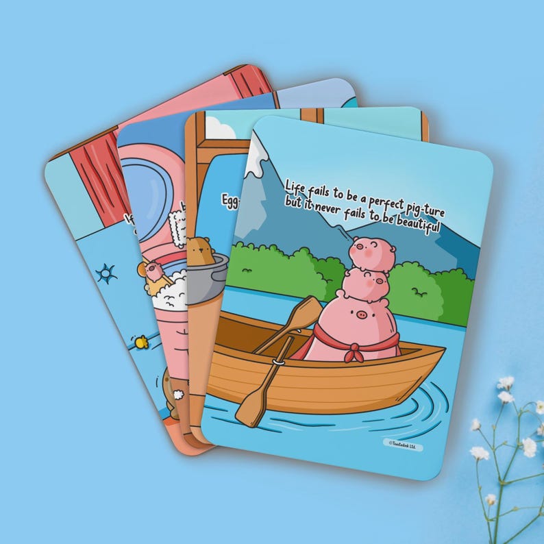 May include: Four illustrated cards with a cute pig theme. The cards feature a pig in a boat, a pig taking a bath, a pig eating an egg, and a pig wearing a crown. The text on the cards reads "Life fails to be a perfect pig-ture but it never fails to be beautiful."
