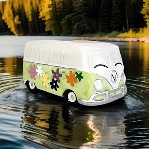 May include: A green and white vintage-style Volkswagen bus with a smiling face and colorful flower decals. The bus is floating on water with ripples around it.