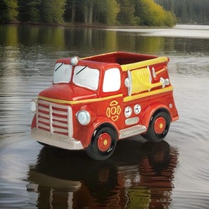 May include: A red and yellow ceramic fire truck planter. The planter features a detailed design with headlights, a ladder, and a hose. The wheels are black with red centers. The planter is sitting in water.