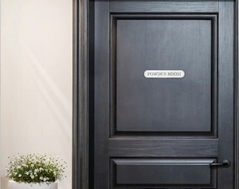 May include: A black door with a silver door handle and a white sign that reads "Powder Room".