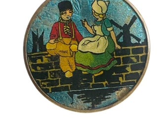 Polvera Art Déco de los años 30 con reverso metalizado, con diseño de pareja holandesa.