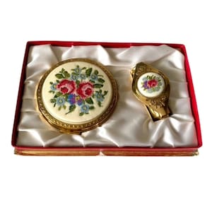 Peut inclure: Un ensemble composé d'un miroir de poche et d'une pince à billets en métal doré, chacun orné d'un médaillon central en broderie petit point représentant des roses rouges et des fleurs bleues sur fond crème, présenté dans un coffret rouge.