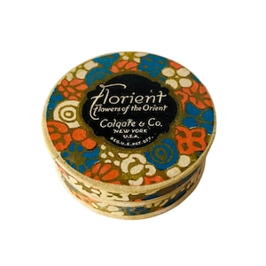 May include: A vintage round box with a floral design in orange, blue, and white. The box has the text "Florient Flowers of the Orient Colgate & Co. New York U.S.A." printed on the top.