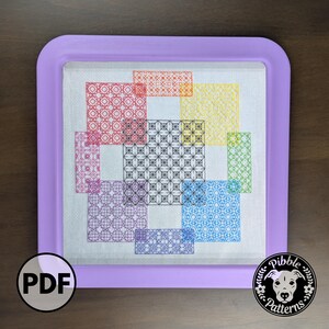 May include: A cross-stitch pattern featuring geometric designs in various colors, including red, yellow, blue, and purple. The stitched artwork is set within a lavender frame. A PDF icon and a logo with a dog's face are visible.