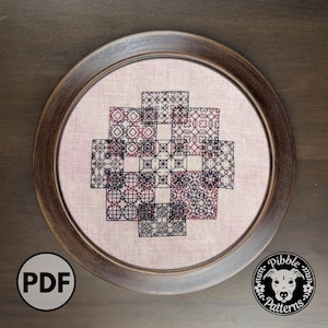 May include: A framed cross-stitch design featuring a geometric pattern in shades of black and burgundy. The design is set against a light pink fabric and enclosed in a round, brown wooden frame. The image includes a "PDF" icon and a logo.