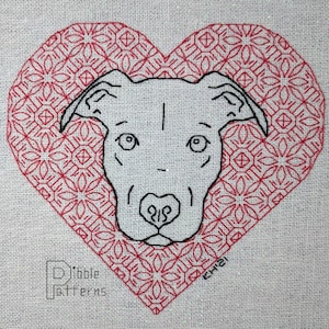 May include: A white dog's face is centered in a red heart with a geometric pattern. The dog has a black nose and black eyes. The text "Pibble Patterns" is in the lower left corner and "CHI" is in the lower right corner.