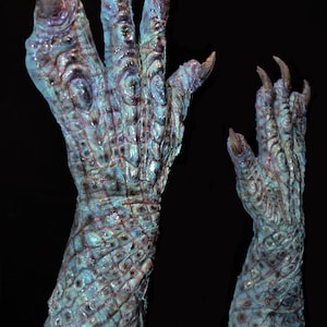 May include: Two blue and purple monster hands with long claws. The hands are textured and have a scaly appearance.