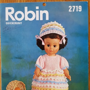 May include: A knitting pattern for a doll's dress and hat. The pattern is called "Robin" and is from the "Quickerknit" line. The dress is pink with yellow and blue trim. The hat is pink with yellow and blue stripes. The pattern number is 2719.