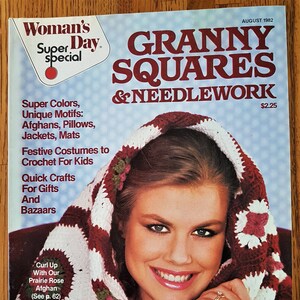 Könnte beinhalten: Ein Magazin-Cover mit einer Frau, die einen rot-weißen Häkel-Schal mit Granny-Square-Mustern trägt. Der Titel des Magazins lautet "Woman's Super Day Special Granny Squares & Needlework" mit dem Text "August 1982" und "2,25 $" in der oberen rechten Ecke. Das Magazin-Cover zeigt den Text "Super Colors, Unique Motifs: Afghans, Pillows, Jackets, Mats" und "Festive Costumes to Crochet For Kids" und "Quick Crafts For Gifts And Bazaars".