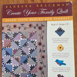 May include: A book by Barbara Brackman titled "Create Your Family Quilt". The cover displays a quilt design with blue, purple, and brown fabric patterns. The book includes over 700 patterns and a design CD. The book's dimensions are in centimetres.