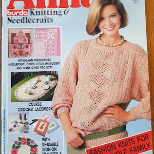 May include: A magazine cover for Anna Burda Knitting & Needlecrafts, featuring a woman wearing a pink knitted sweater and a green belt. The cover text reads "Fashion Knits for the Whole Family" and "August 1985".