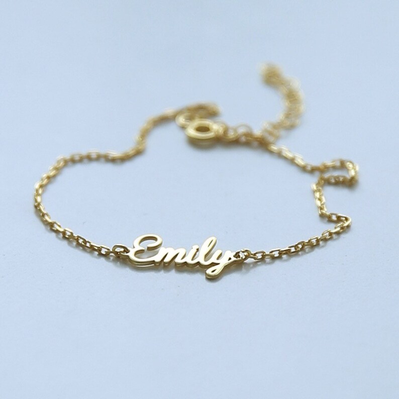 May include: A gold chain bracelet with the name "Emily" spelled out in cursive.