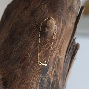 May include: A gold chain necklace with the name "Emily" spelled out in cursive.