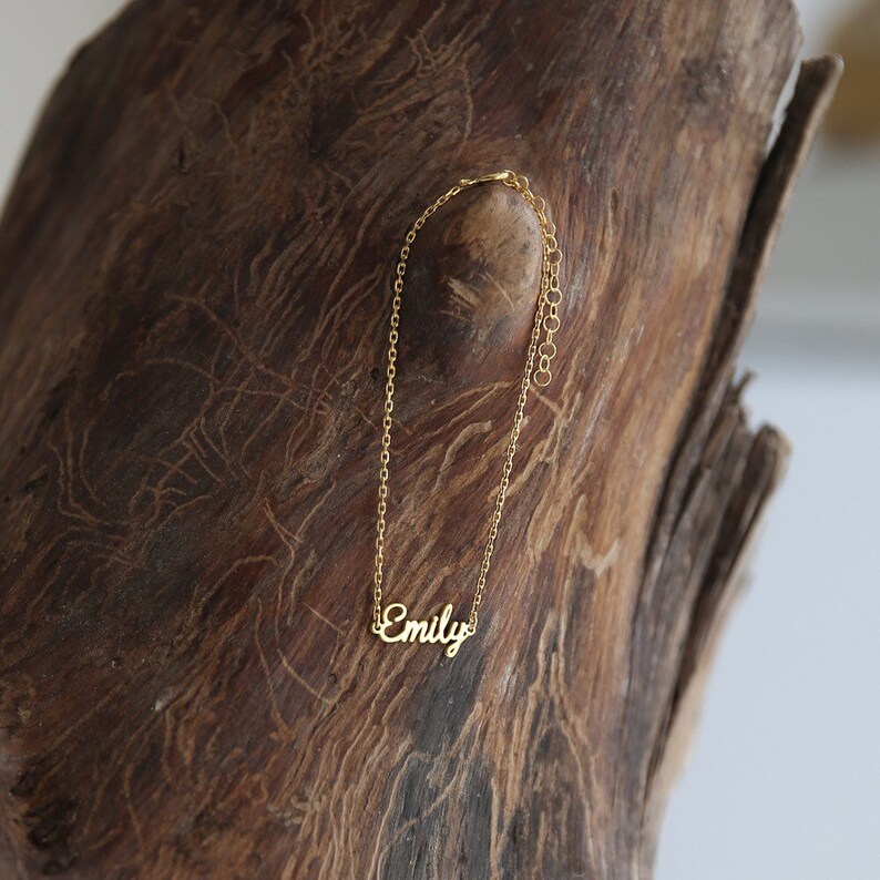 May include: A gold chain necklace with the name "Emily" spelled out in cursive.