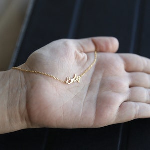May include: A gold chain necklace with the name "Emily" spelled out in cursive.