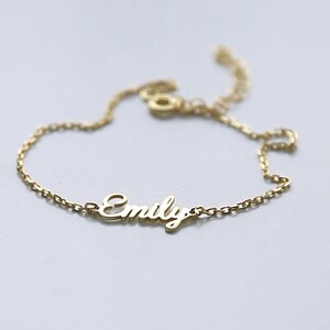 May include: A gold chain bracelet with the name "Emily" spelled out in cursive.