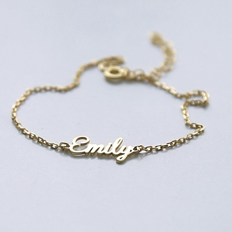 May include: A gold chain bracelet with the name "Emily" spelled out in cursive.