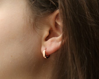 Op de afbeelding: Een close-up van een oor met een kleine, roségouden oorring. De oorring is simpel en elegant, en zou een geweldige aanvulling zijn op elke sieradencollectie.