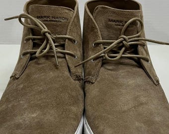 May include: Pair of brown suede chukka boots with white soles. The boots have laces and a pull tab at the back. The brand name "MARK NASON" is visible on the tongue of each boot.