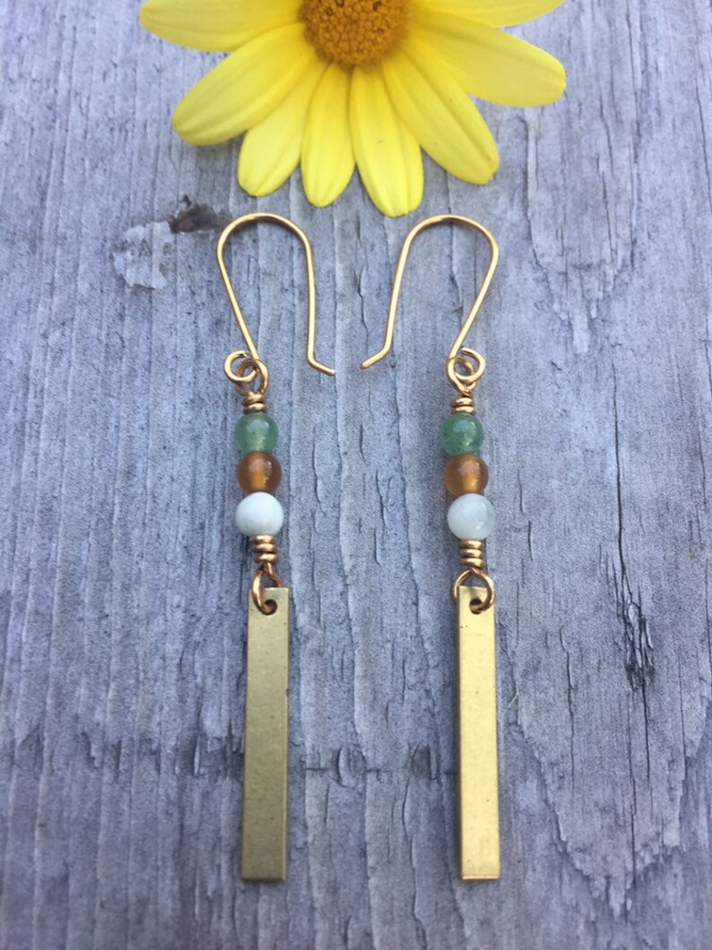 May include: Gold dangle earrings with green, white, and brown beads and a gold bar pendant.