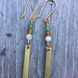 May include: A pair of gold earrings with green, amber, and white beads and a gold bar pendant.