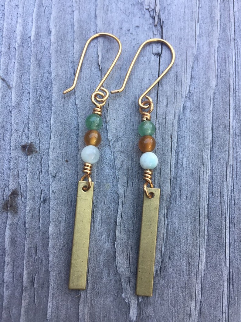 May include: A pair of gold earrings with green, amber, and white beads and a gold bar pendant.