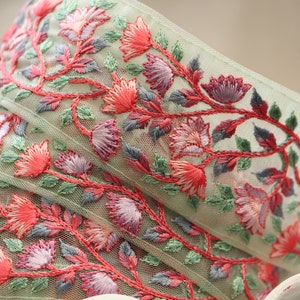 May include: Green tulle ribbon with pink and red embroidered floral designs.