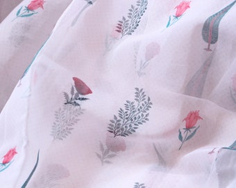 Puede incluir: Tela blanca transparente con estampado floral de flores rosas y verdes. La tela es suave y delicada, perfecta para crear prendas o decoración del hogar.