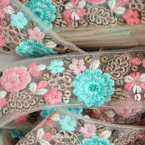 May include: Beige lace trim with pink and turquoise embroidered flowers and gold sequins.