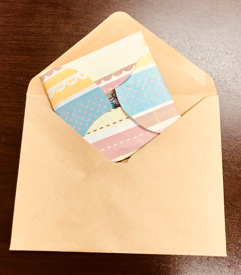 May include: A brown paper envelope with a colourful patterned card inside. The card has stripes, polka dots, and scalloped edges.
