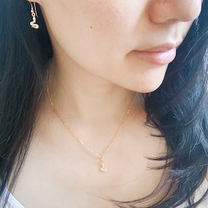 May include: A gold chain necklace with a small, sparkling pendant. The pendant is shaped like a cloud with a single, clear stone in the center.