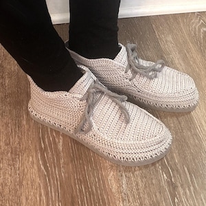 May include: A white ceramic mug with a black handle and the text "But First, Coffee" in a handwritten style. The mug is on a white surface. The mug is approximately 4 inches tall.