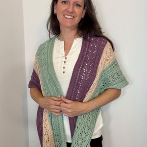 May include: A multi-colored shawl with a lace design. The shawl features stripes of light green, tan, and purple. The shawl is draped over the shoulders.